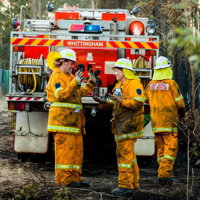 Image of three female volunteer firefighters talking together behind a firetruck in Whittingham in the Hunter region