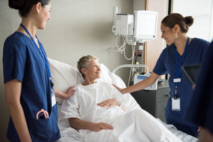 Image of a woman in her hospital bed talking to doctors