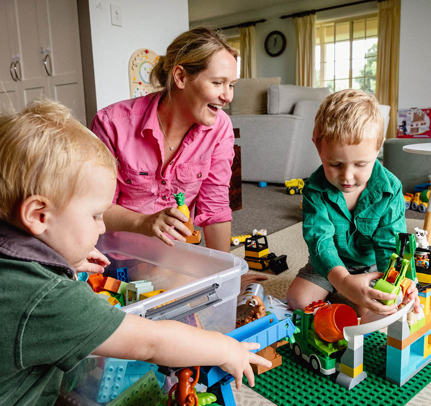 A woman playing lego toys with two child in a living room 