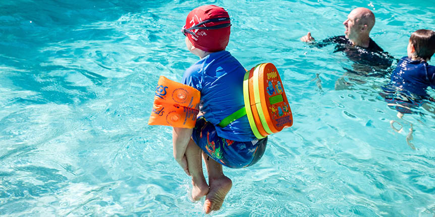 A group of people playing in a backyard swimming pool