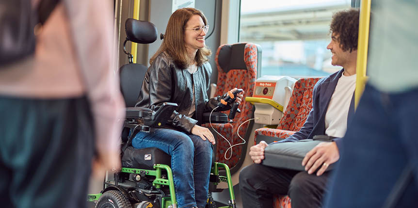 A passenger who uses a motorised wheelchair charging phone at a charging point in the accessible area of an intercity train