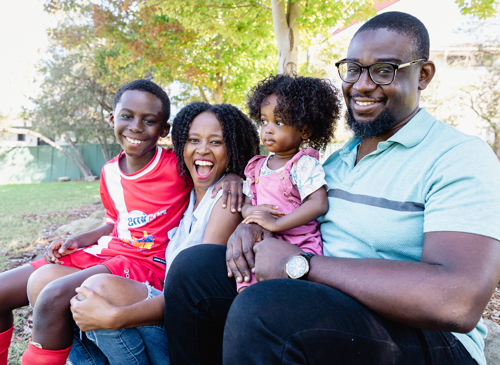 A family sitting in a park smiling at the camera