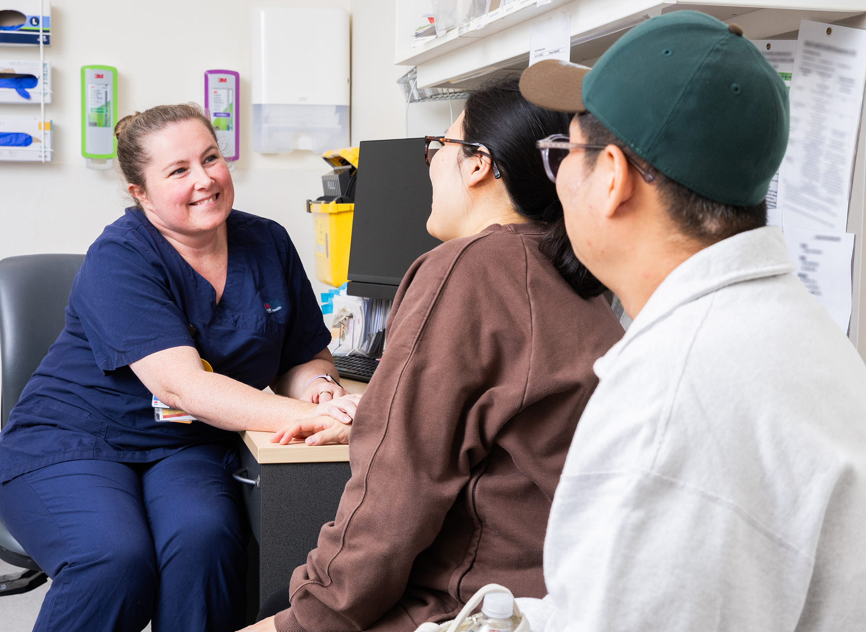 A healthcare professional talking to two people in a consult room