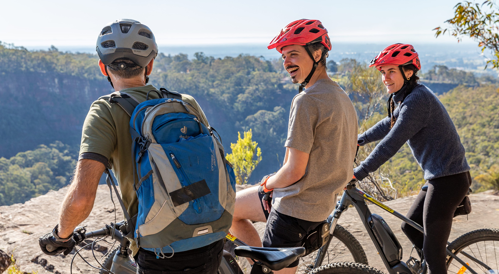 A group of people with helmets on bikes looking over a lookout