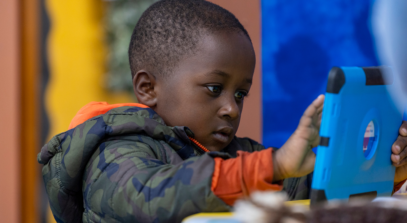 A young child playing with a digital tablet