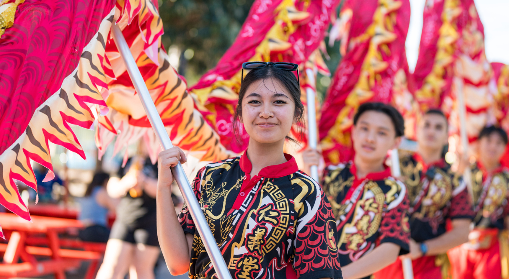 A group of people in traditional garments holding a dragon at a street parade
